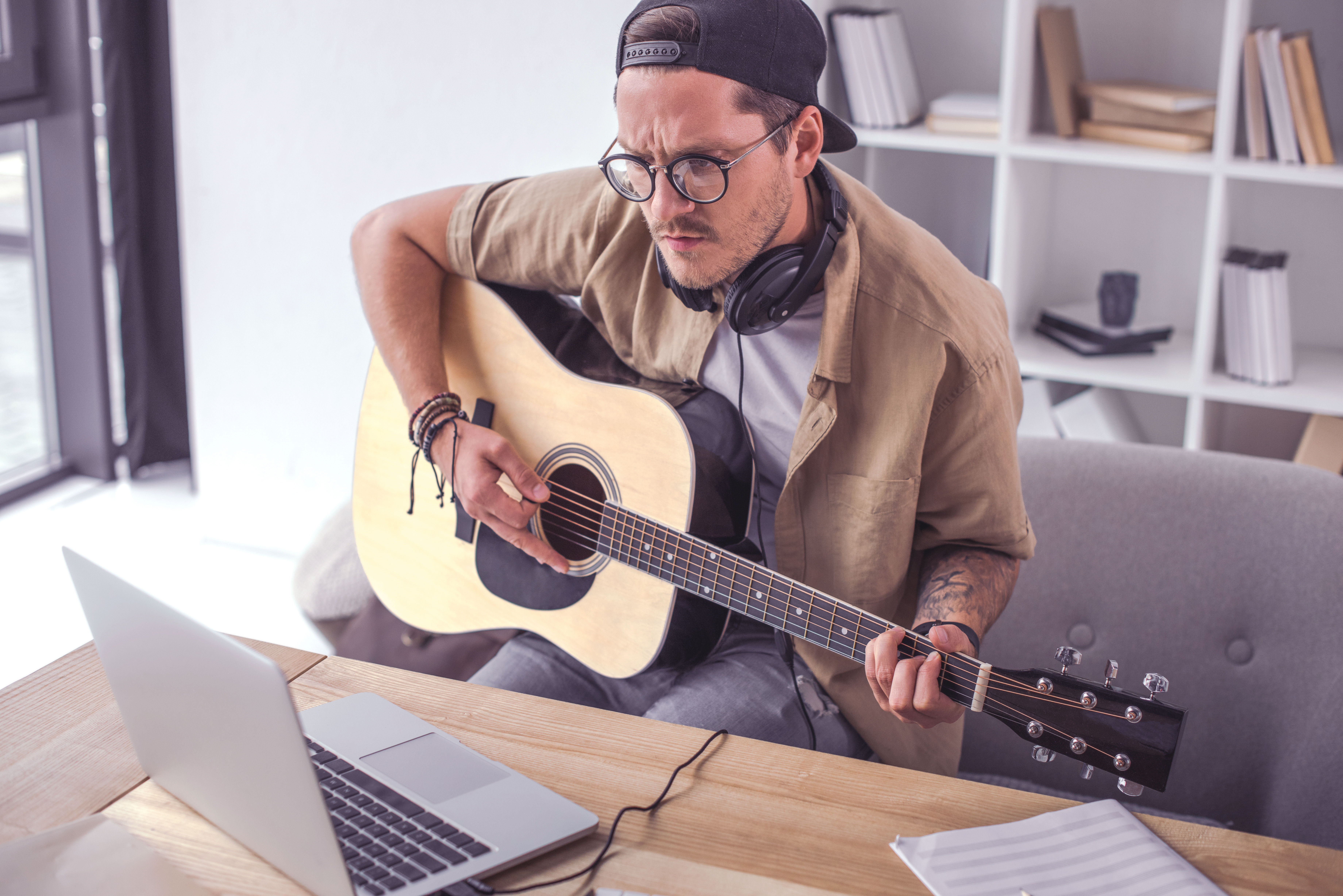 Image of young man playing guitar looking at a laptop