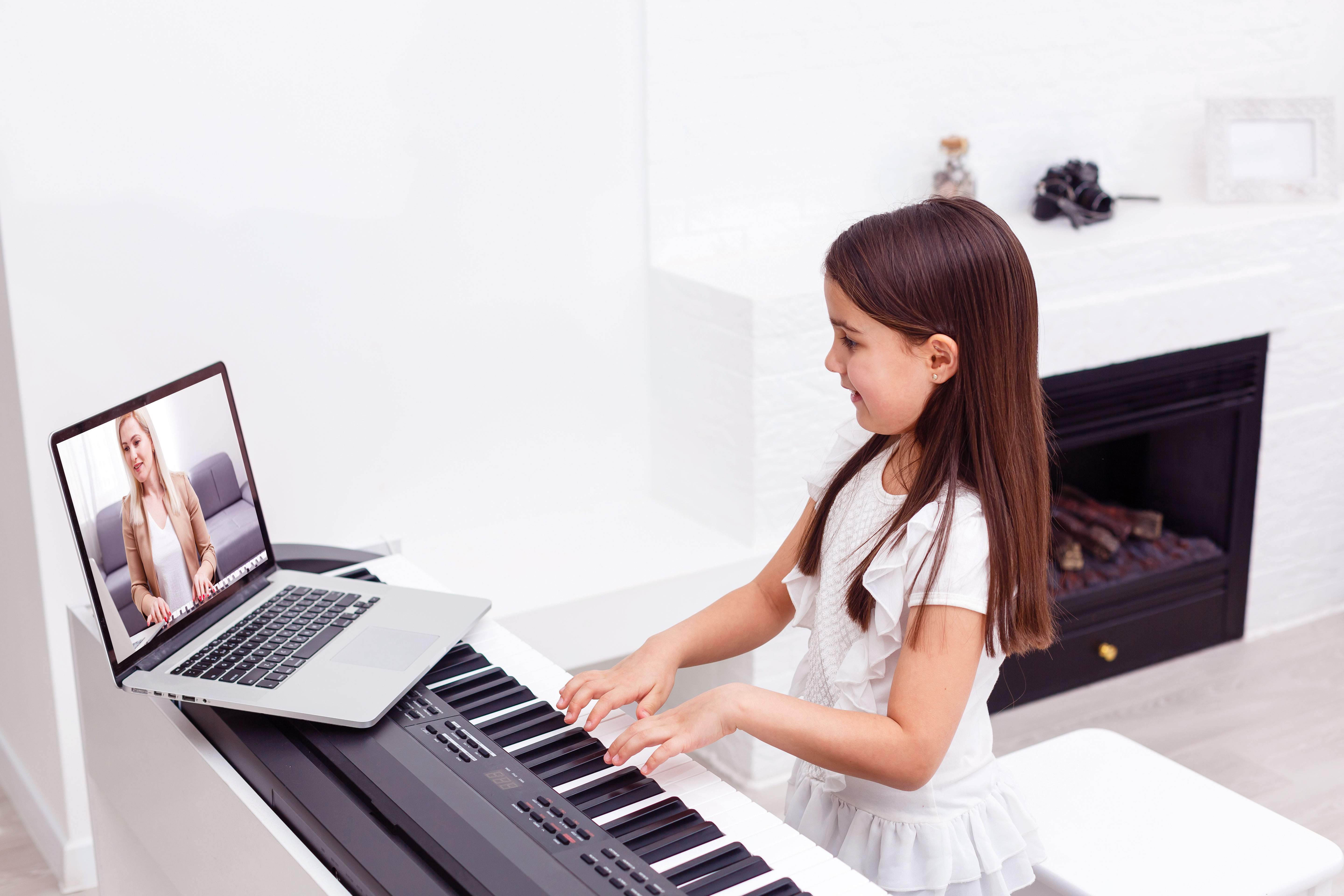 Image of a girl having an online piano lesson smiling at a laptop