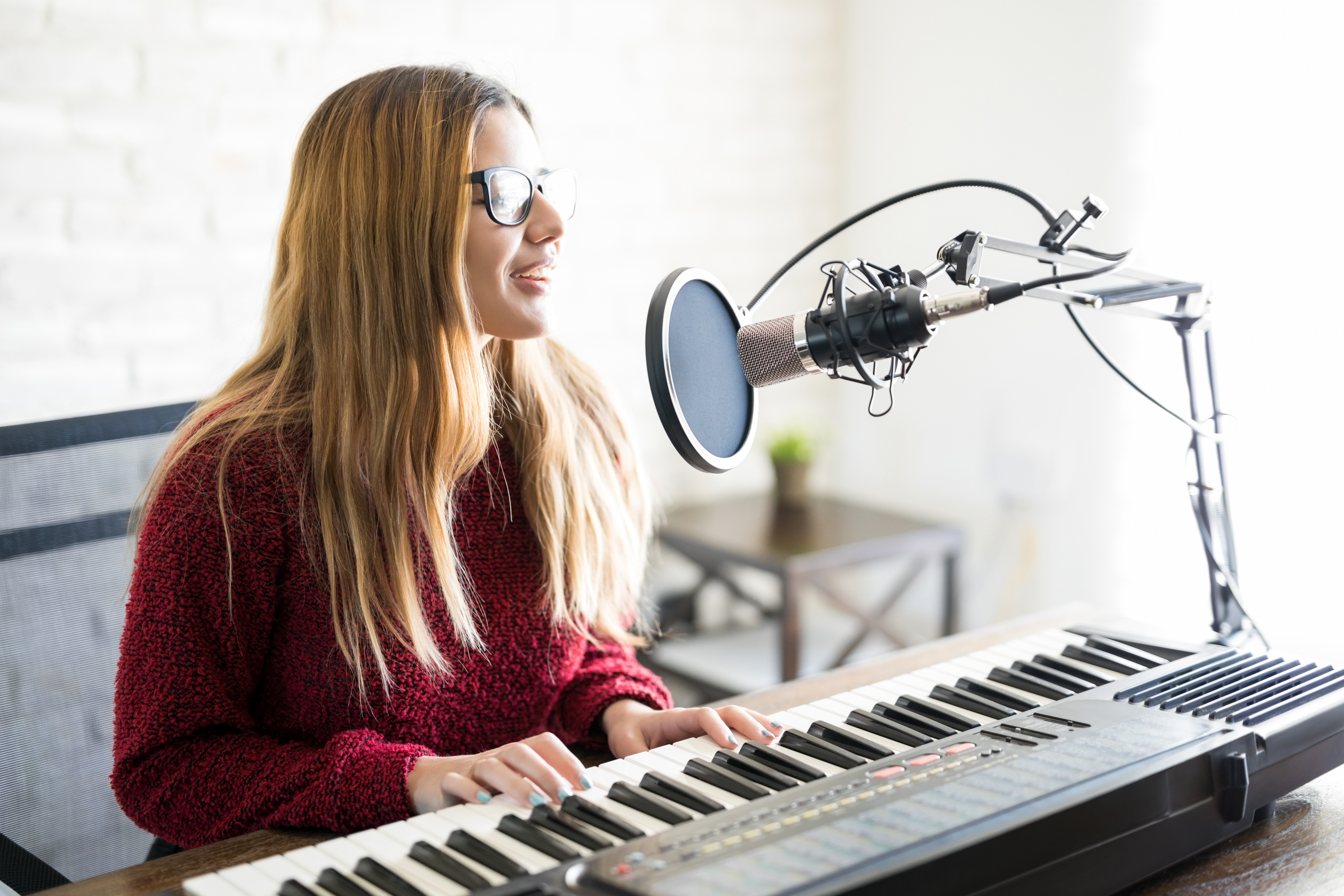 Image of young woman playing piano and singing into a microphone
